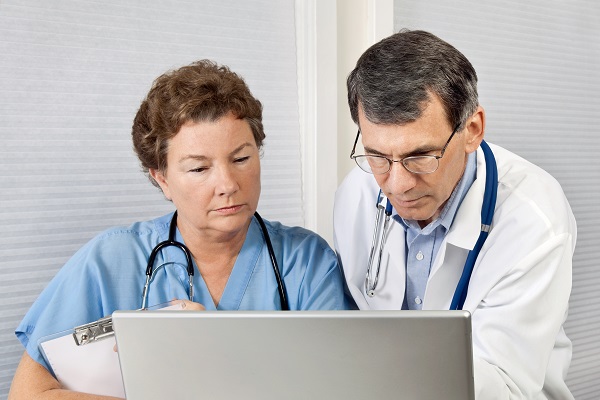 Doctor And Nurse Talking and Working at Laptop Computer In Office